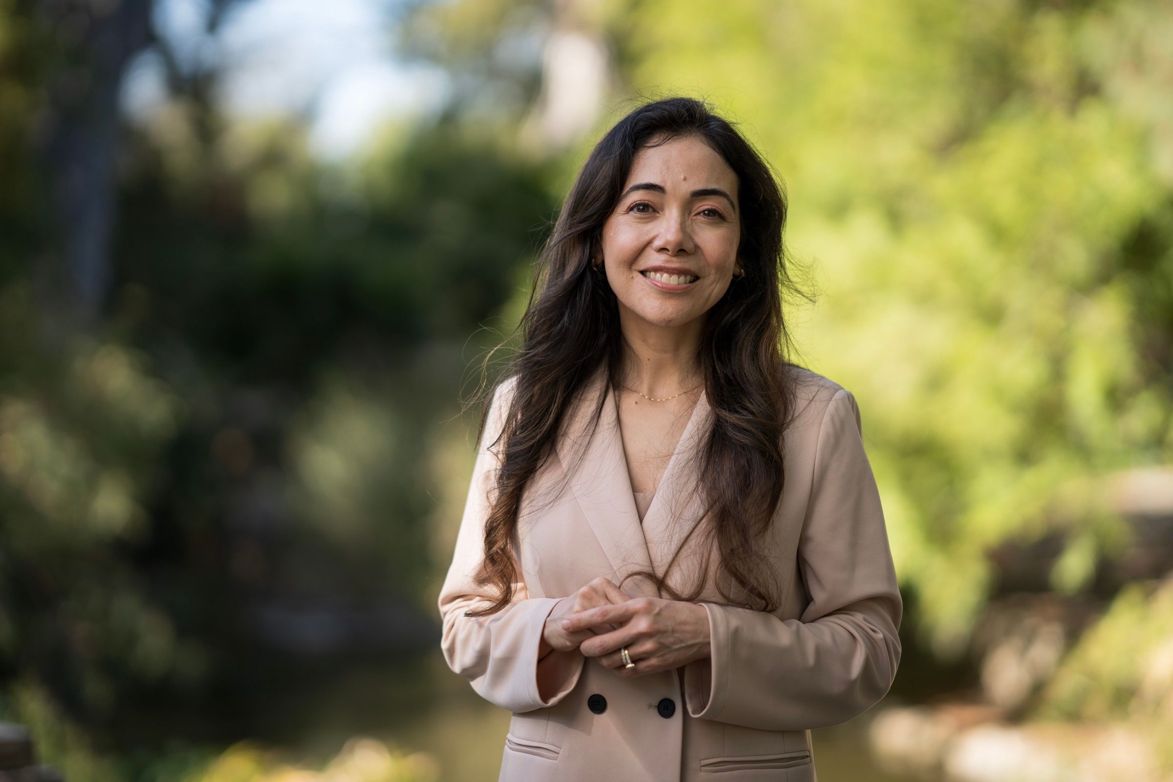 Woman in a beige suit posing for an outdoor professional portrait.