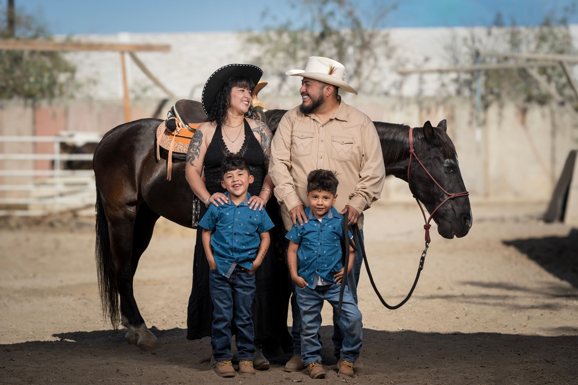 Western-themed family of four posing beside a saddled horse.